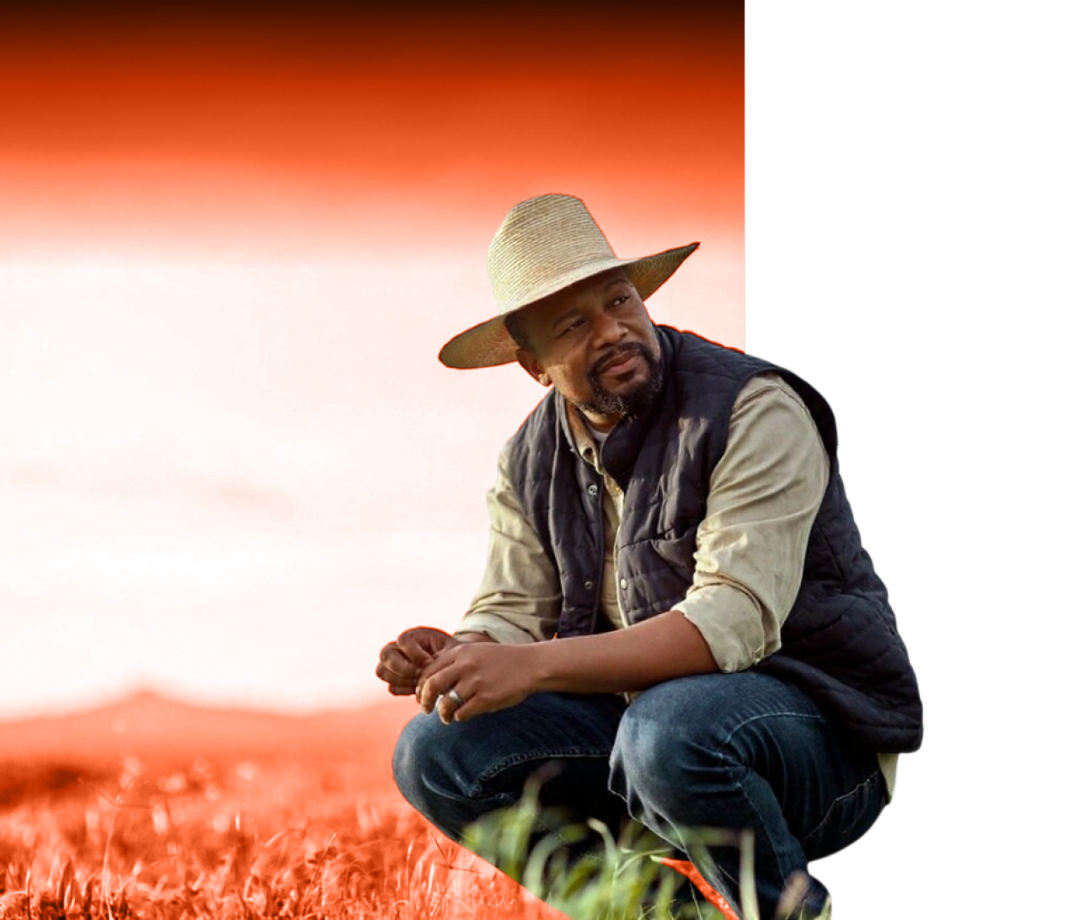 A farmer crouching in a field at golden hour